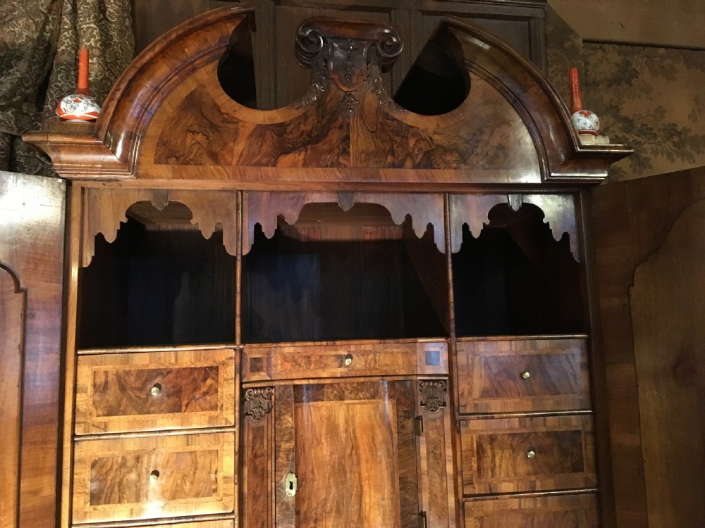 A George I walnut bureau bookcase featuring an arched pediment, two mirrored doors on the upper cabinet, and a sloping fall-front desk over three long drawers. View V
