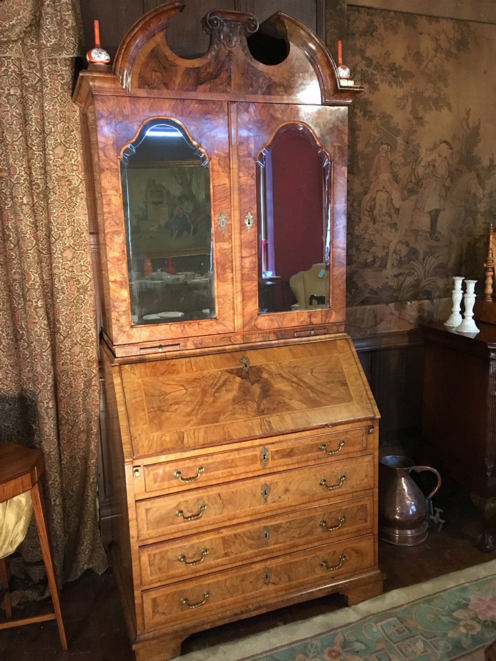 A George I walnut bureau bookcase featuring an arched pediment, two mirrored doors on the upper cabinet, and a sloping fall-front desk over three long drawers. View VI