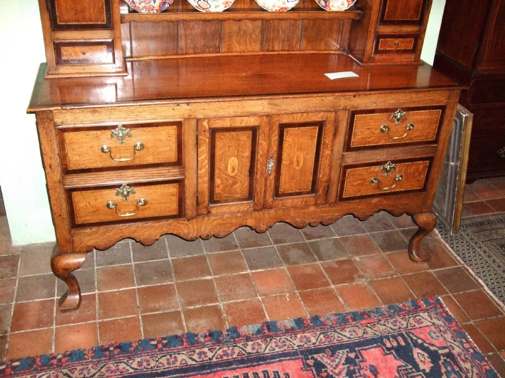 An 18th-century George III oak Welsh dresser featuring a stepped upper plate rack flanked by inlaid side cupboards over a lower base with drawers and cabriole legs. View II