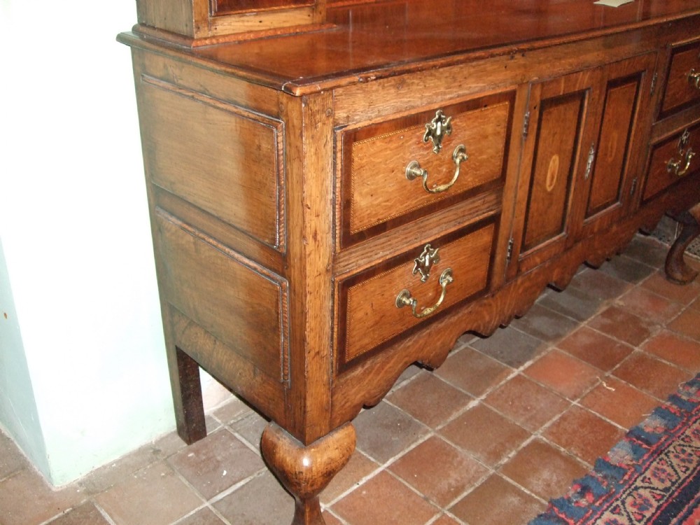 An 18th-century George III oak Welsh dresser featuring a stepped upper plate rack flanked by inlaid side cupboards over a lower base with drawers and cabriole legs. View III