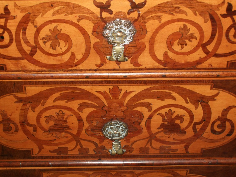 A William and Mary walnut chest of drawers featuring ornate floral marquetry inlays, brass drop handles, and turned bun feet. View III