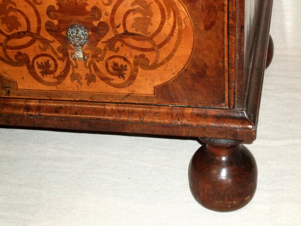 A William and Mary walnut chest of drawers featuring ornate floral marquetry inlays, brass drop handles, and turned bun feet. View IV