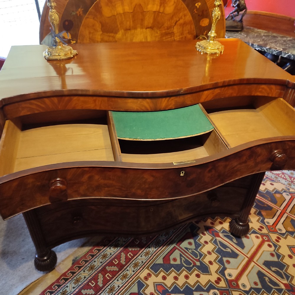 A William IV flame mahogany chest featuring four graduated serpentine drawers with reeded side columns and turned lobed feet. View IV