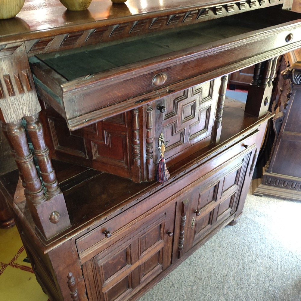 A late 17th-century dark oak court cupboard featuring geometric panel doors and turned baluster supports. View II