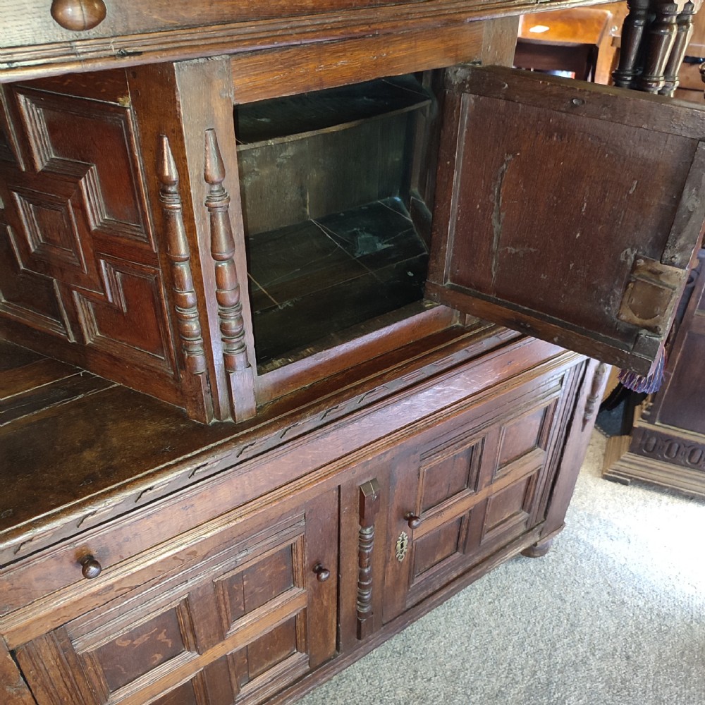 A late 17th-century dark oak court cupboard featuring geometric panel doors and turned baluster supports. View III