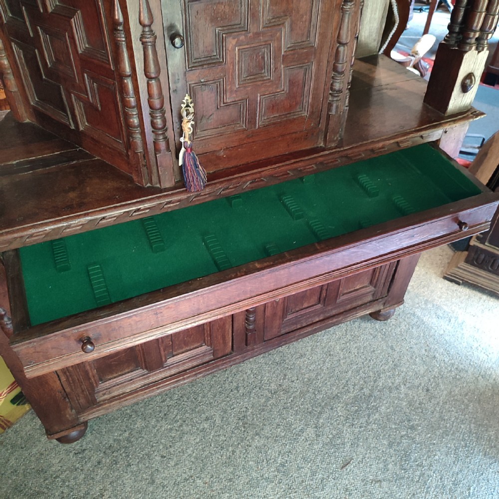A late 17th-century dark oak court cupboard featuring geometric panel doors and turned baluster supports. View IV
