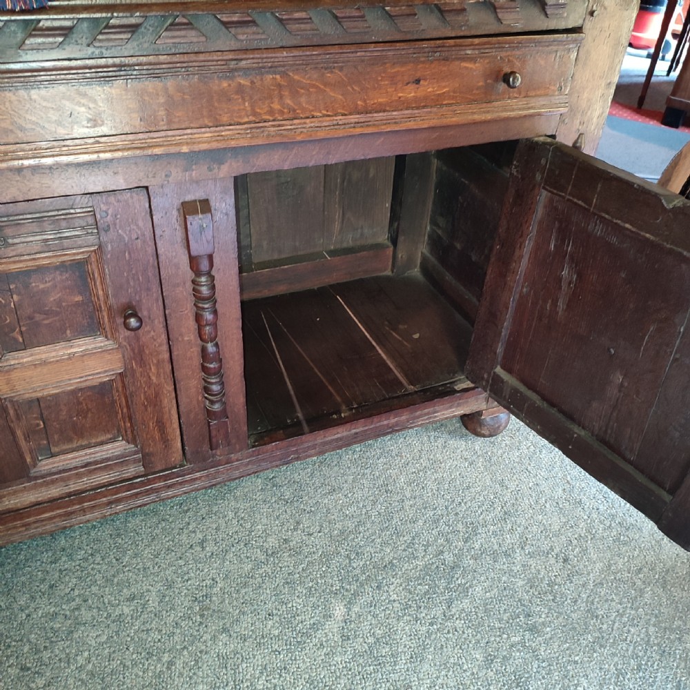 A late 17th-century dark oak court cupboard featuring geometric panel doors and turned baluster supports. View V
