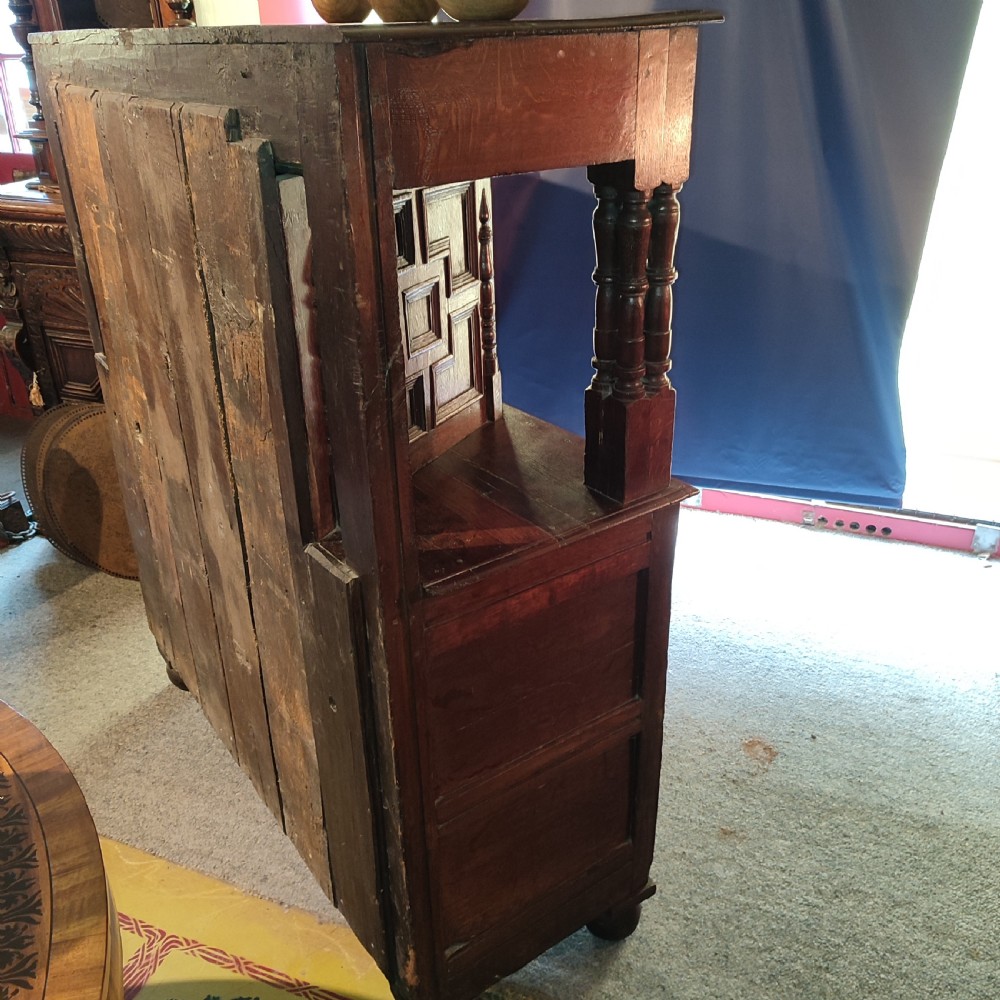 A late 17th-century dark oak court cupboard featuring geometric panel doors and turned baluster supports. View VI