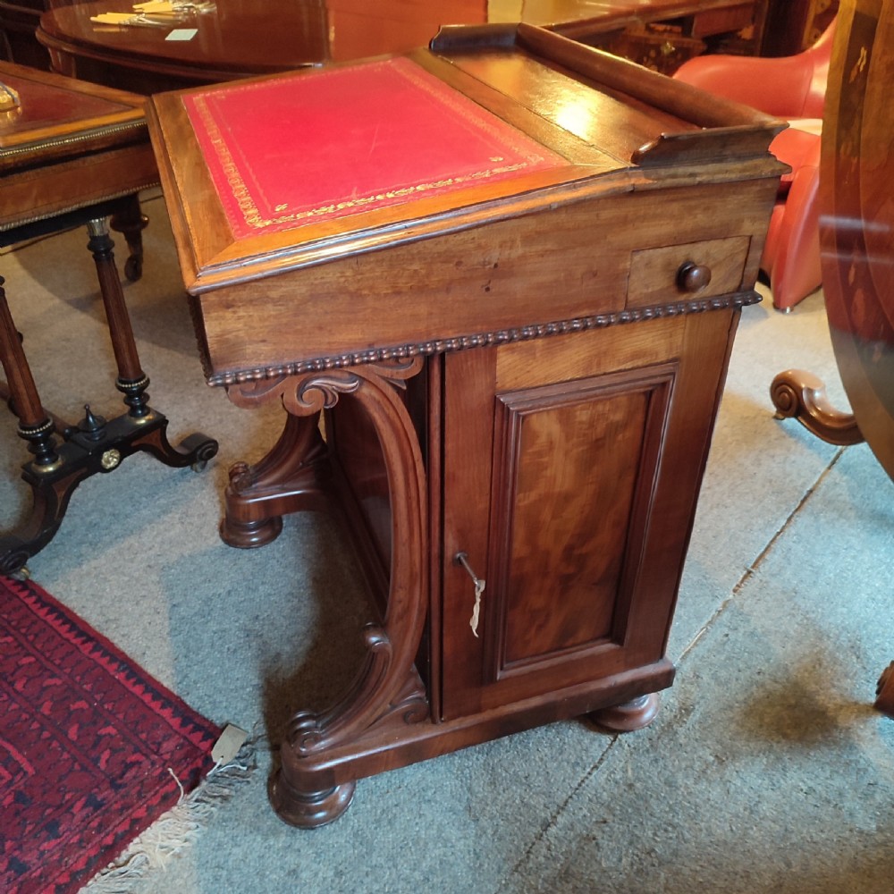 A Regency mahogany davenport desk featuring a red leather-lined sloped writing top, carved scroll supports, and beaded edging. View II