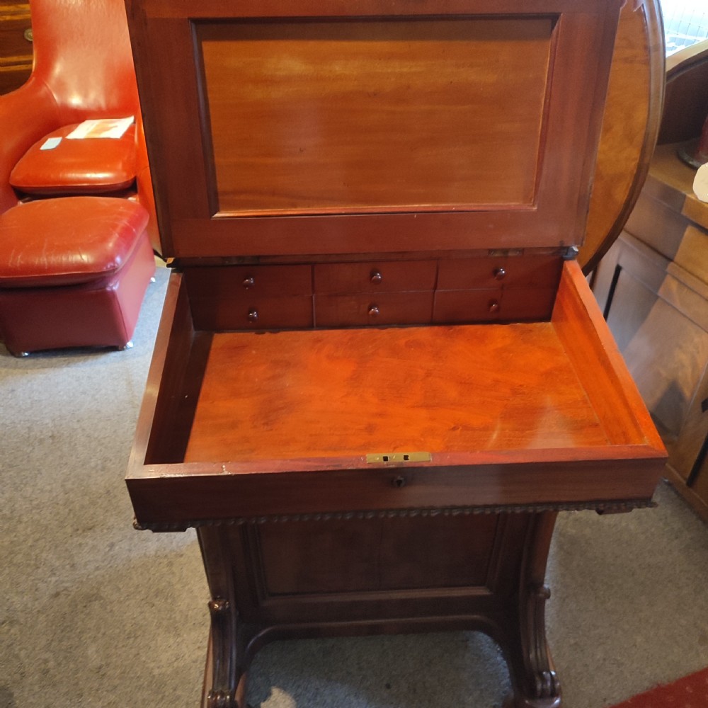 A Regency mahogany davenport desk featuring a red leather-lined sloped writing top, carved scroll supports, and beaded edging. View III
