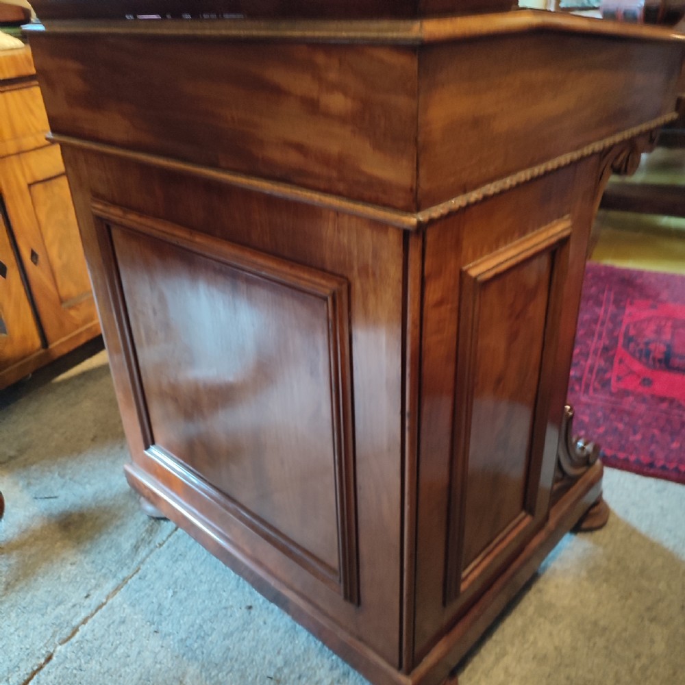 A Regency mahogany davenport desk featuring a red leather-lined sloped writing top, carved scroll supports, and beaded edging. View V