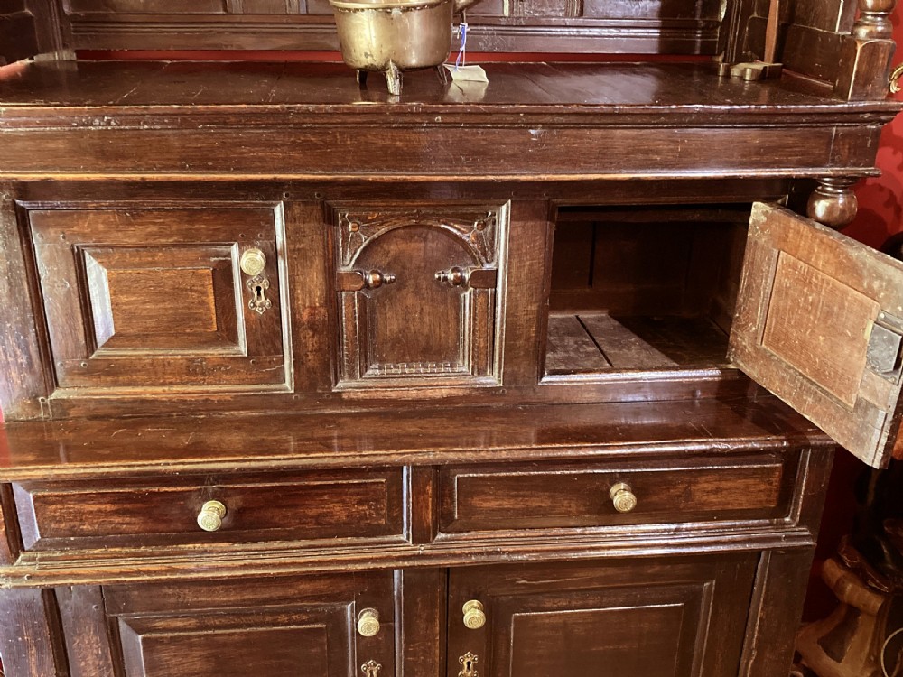 An early eighteenth-century dark oak three-tier Welsh tridarn featuring an open upper canopy, panelled cupboard doors, drawers, and turned balusters. View II