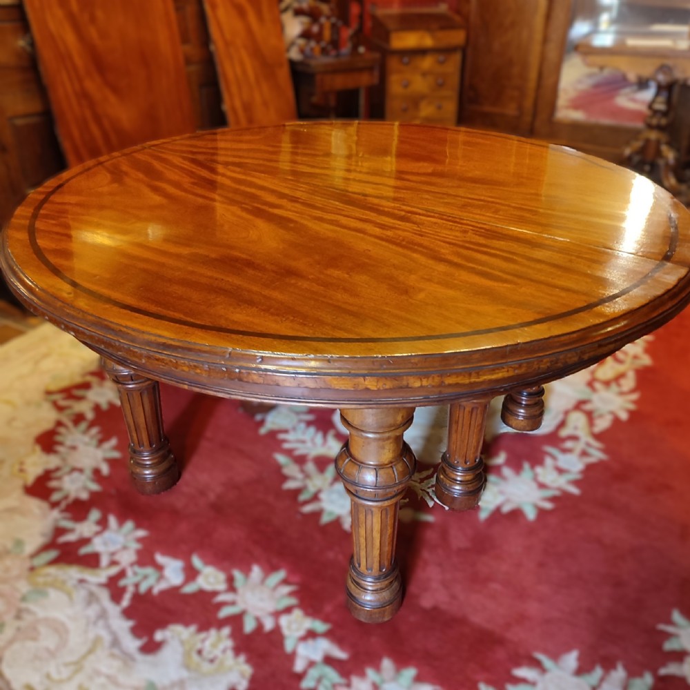 A large Victorian extending mahogany dining table featuring a polished surface with crossbanded inlay and turned fluted legs. View III