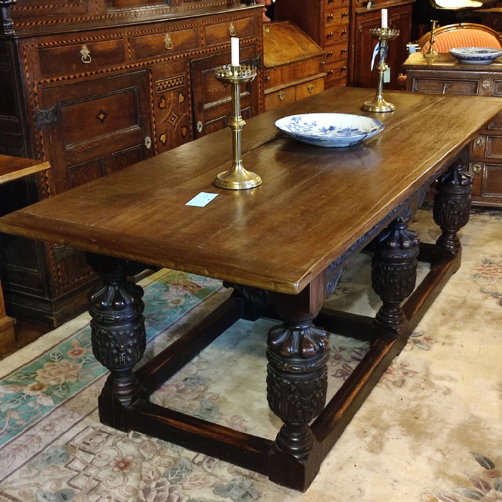 A long 19th-century oak and red walnut refectory table featuring heavily carved bulbous legs joined by a low perimeter box stretcher.