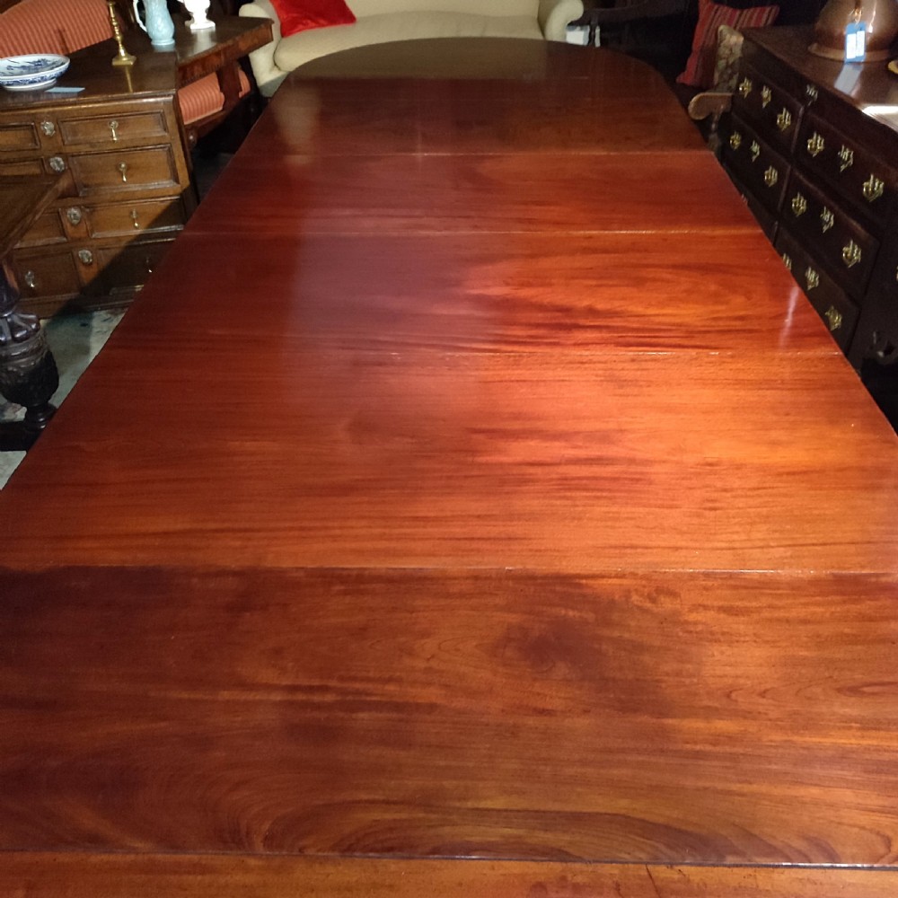 A large 19th-century mahogany extending dining table featuring a polished surface, rounded ends, and thick turned legs on casters. View IV