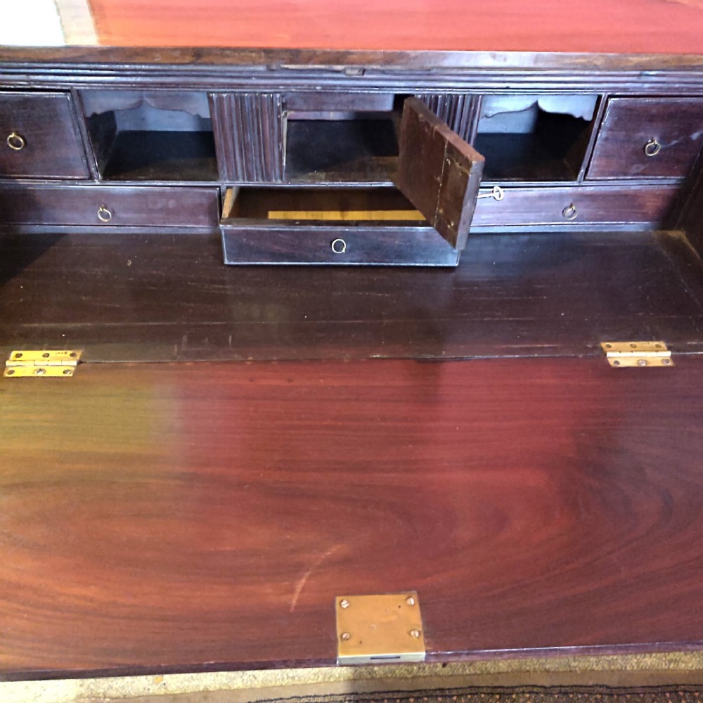 A nineteenth-century padouk wood campaign bureau featuring brass inlay, flush brass drawer handles, protective brass corner brackets, and a slanted fall-front writing flap. View III
