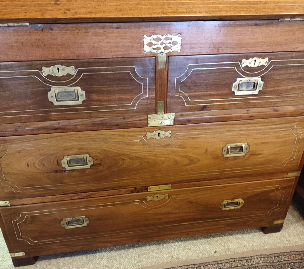 A nineteenth-century padouk wood campaign bureau featuring brass inlay, flush brass drawer handles, protective brass corner brackets, and a slanted fall-front writing flap. View V