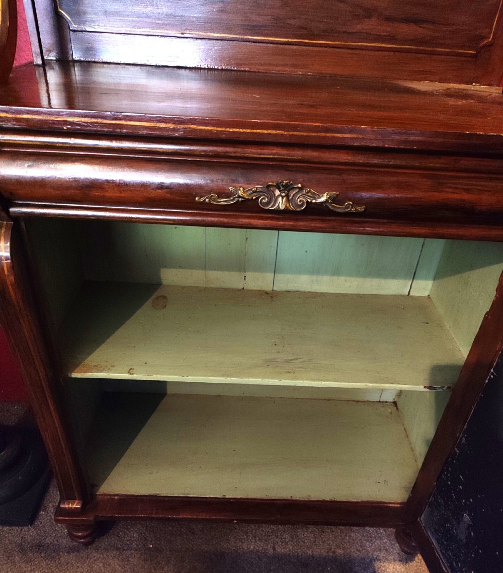 A Regency simulated rosewood chiffonier featuring a raised gallery shelf on S-scroll supports, gold line detailing, and a lower door with a pleated green fabric panel. View II