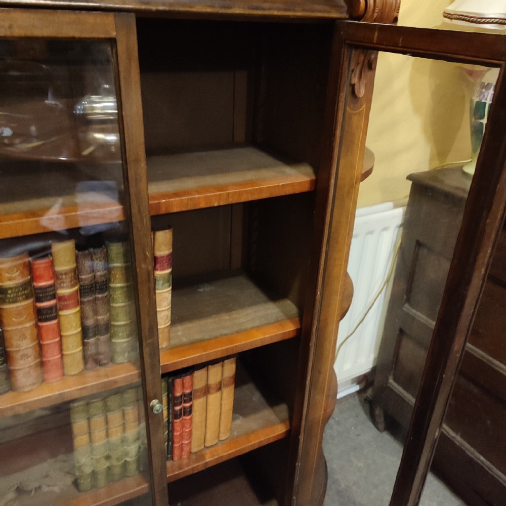 An antique Victorian walnut glazed bookcase featuring double glass doors flanked by open curved side shelves and carved corbels. View IV