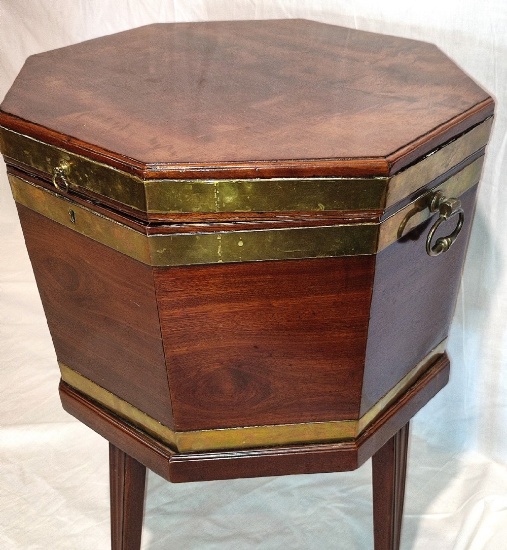 An octagonal Regency mahogany cellarette with brass banding, raised on fluted tapered legs with brass castors. View II