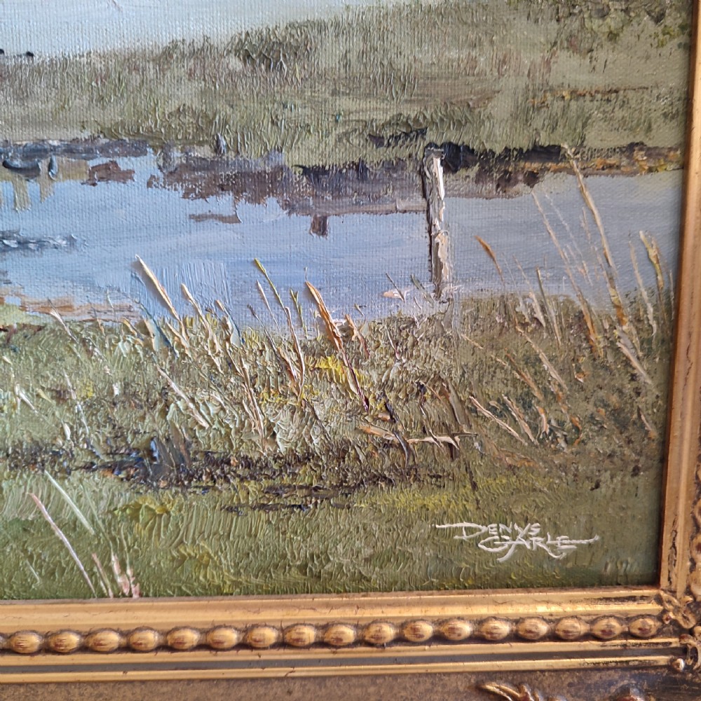 An original 20th-century oil painting depicting a coastal landscape with small cottages, boats, and distant mountains, set in a carved gold gilded frame. View III