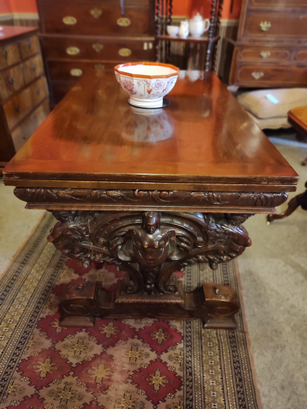 A 19th-century dark walnut extending dining table featuring a polished rectangular top with fully extended side leaves, supported on a heavily carved stretcher base. View II