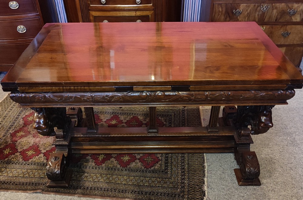 A 19th-century dark walnut extending dining table featuring a polished rectangular top with fully extended side leaves, supported on a heavily carved stretcher base. View III