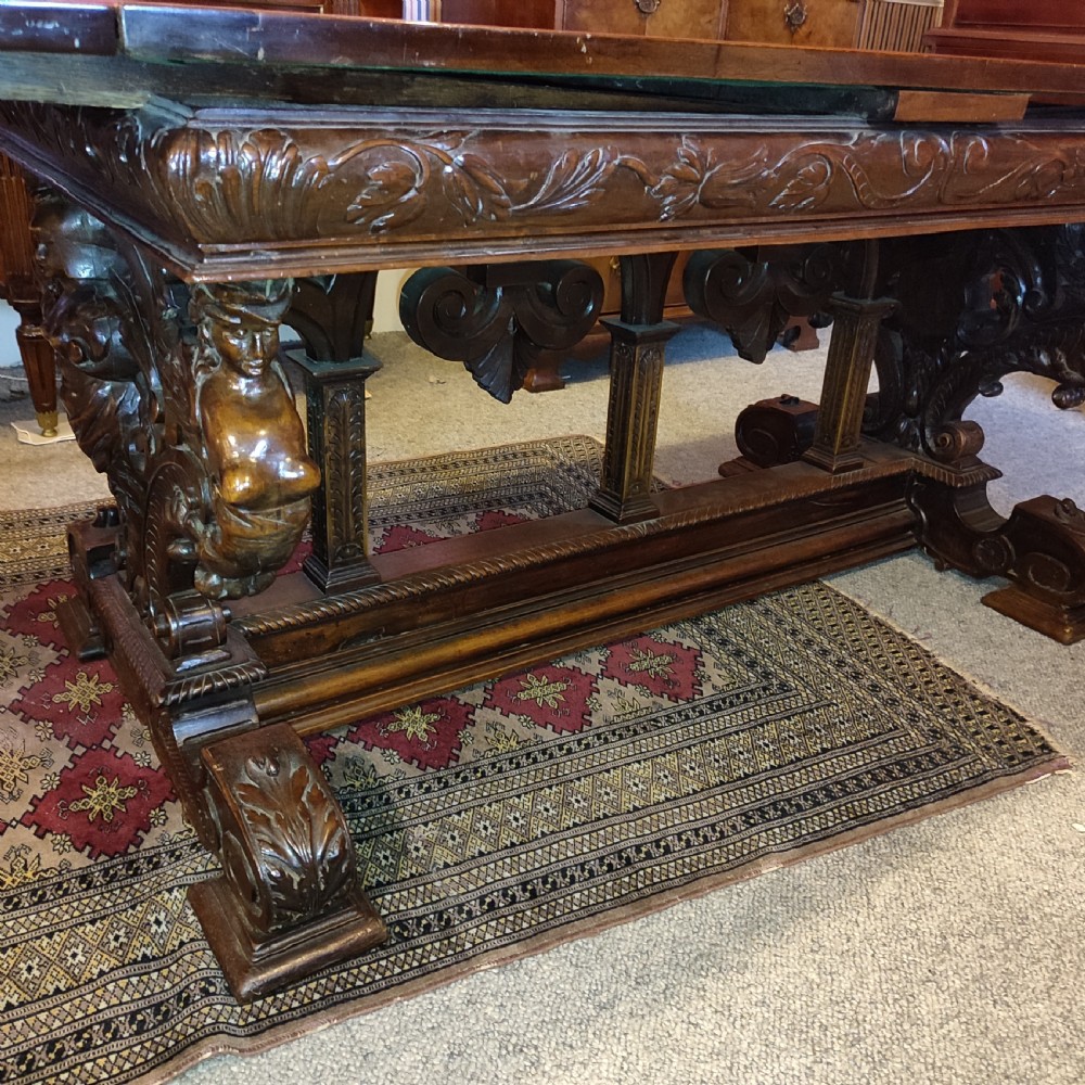 A 19th-century dark walnut extending dining table featuring a polished rectangular top with fully extended side leaves, supported on a heavily carved stretcher base. View V