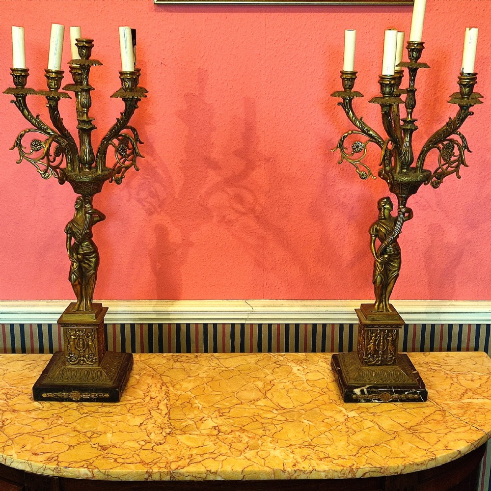 A pair of early 20th-century gilt metal five-light candelabra with classical female figure standards on marble plinths.