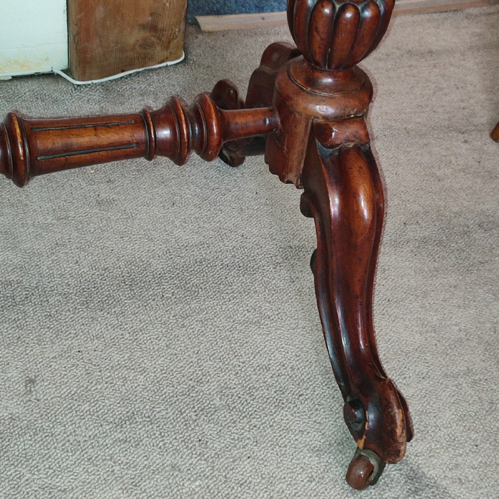 A Victorian walnut centre table with a shaped polished top, turned twin-column supports, a carved central stretcher, and cabriole legs with castors. View III