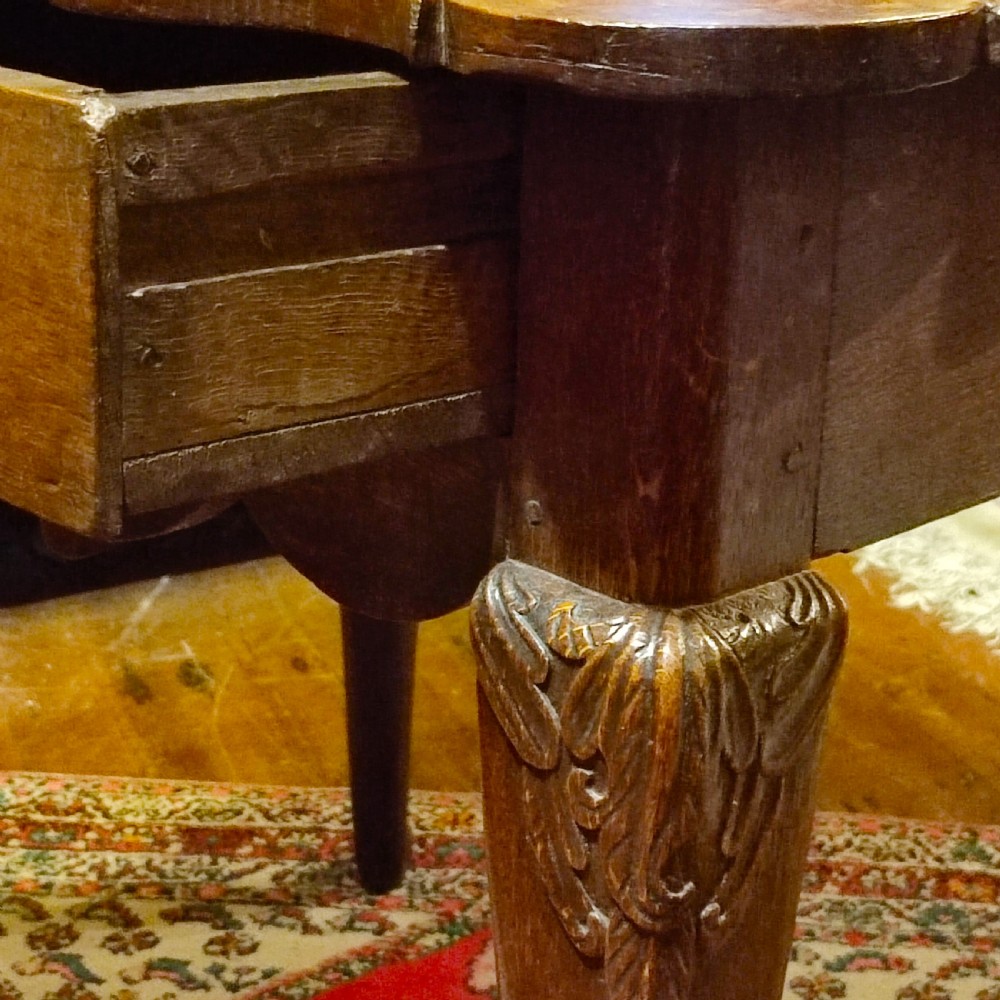 An 18th-century oak lowboy featuring a scalloped edge top, a single drawer with brass drop handles, a shaped apron, and carved cabriole legs. View IV
