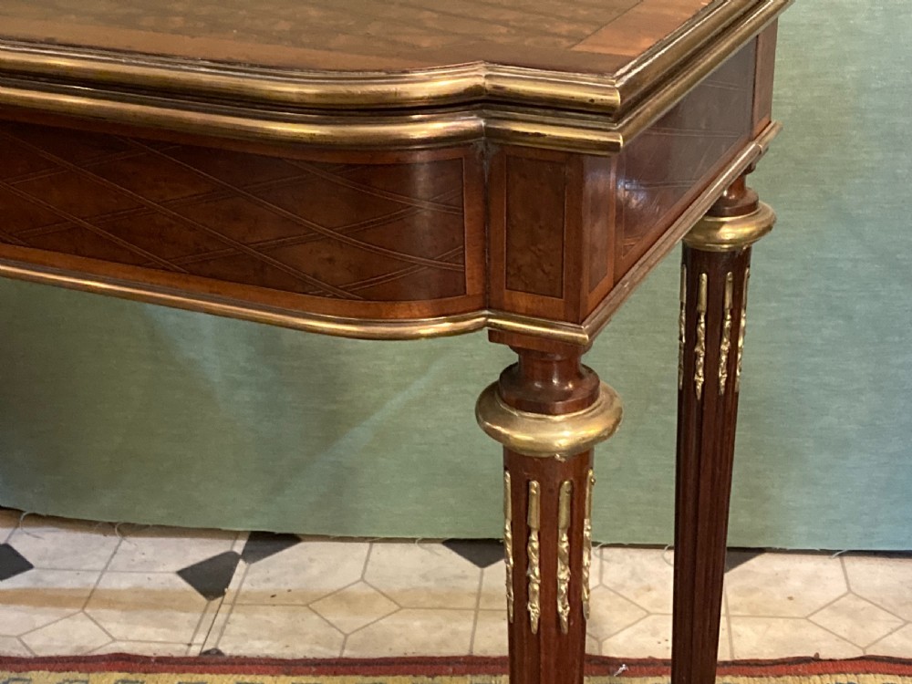 A 19th-century walnut card table featuring a floral marquetry top, brass ormolu trim, fluted tapering legs, and a hinged flip-top. View II