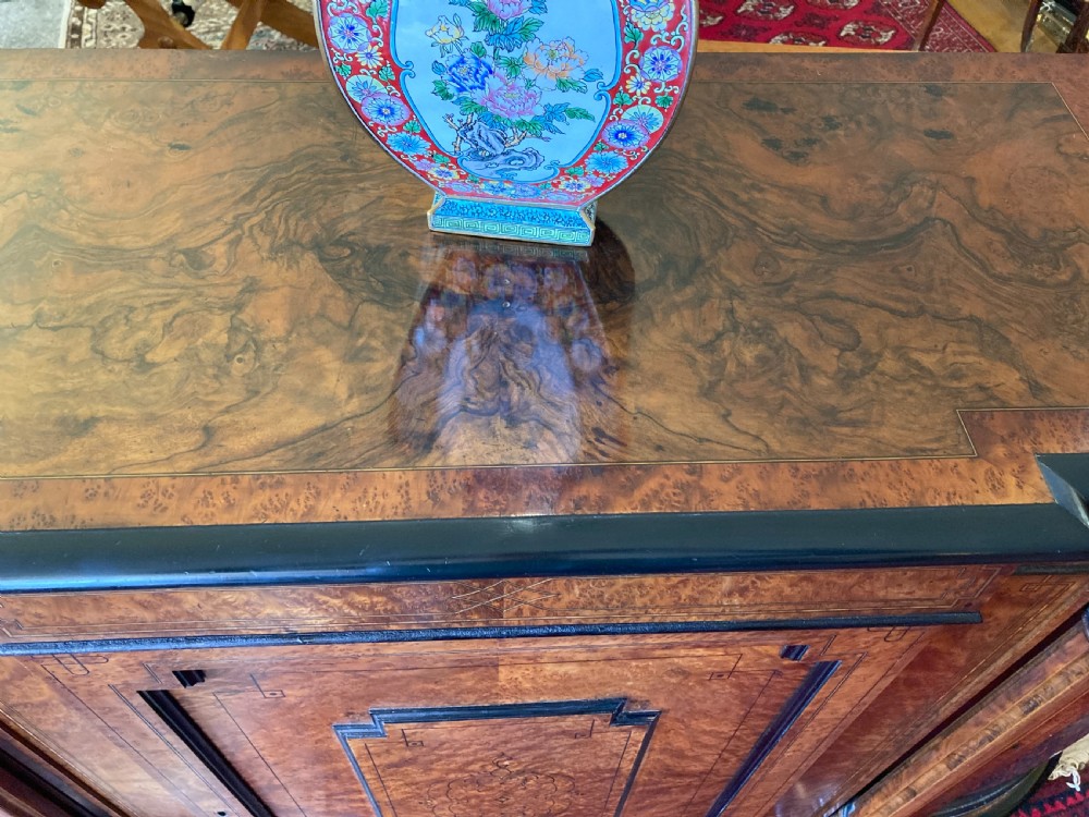 A Victorian amboyna and ebonised credenza featuring a central inlaid door panel, turned columns, and curved glass side doors. View VIII
