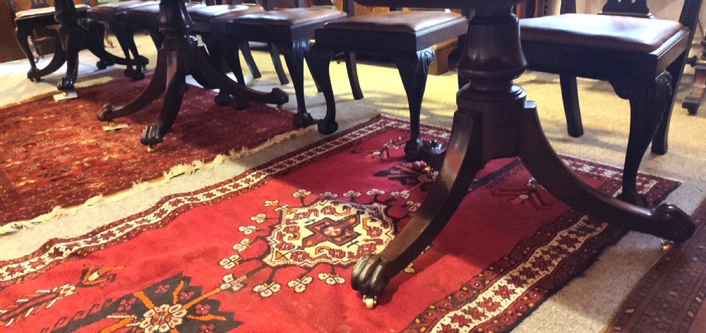 A long, highly polished George III mahogany triple pedestal dining table featuring rounded edge corners and central support columns. View III