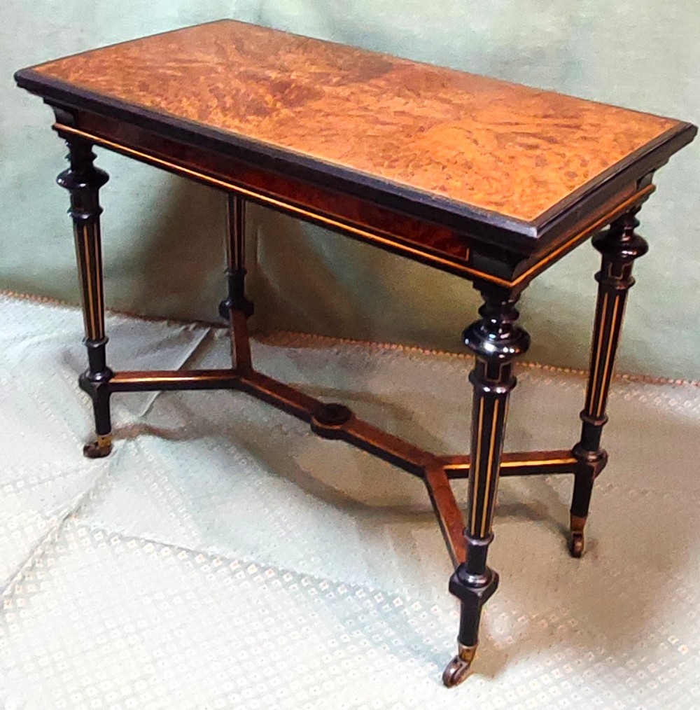 An antique amboyna and ebony card table featuring intricate wood grain and turned legs.
