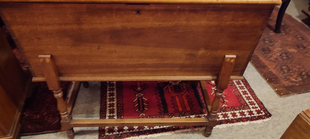 A 19th-century walnut dough bin featuring a rectangular hinged lid, clean panelled sides, an iron keyhole escutcheon, turned lower legs, and horizontal stretchers. View IV