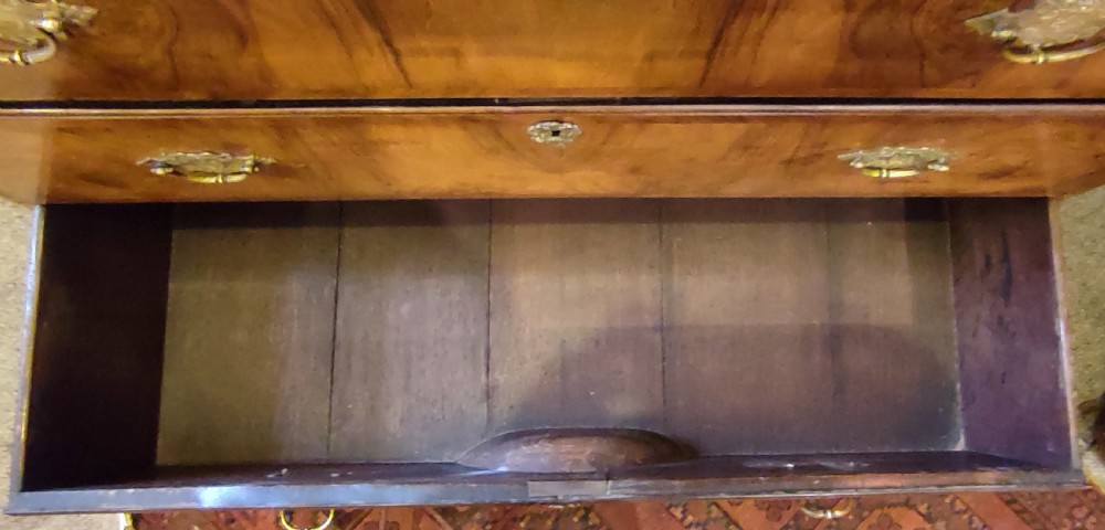 An 18th-century George II walnut chest-on-chest featuring stacked drawers with brass handles and a sunburst inlay on the bottom drawer. View V