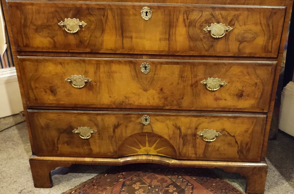 An 18th-century George II walnut chest-on-chest featuring stacked drawers with brass handles and a sunburst inlay on the bottom drawer. View VII