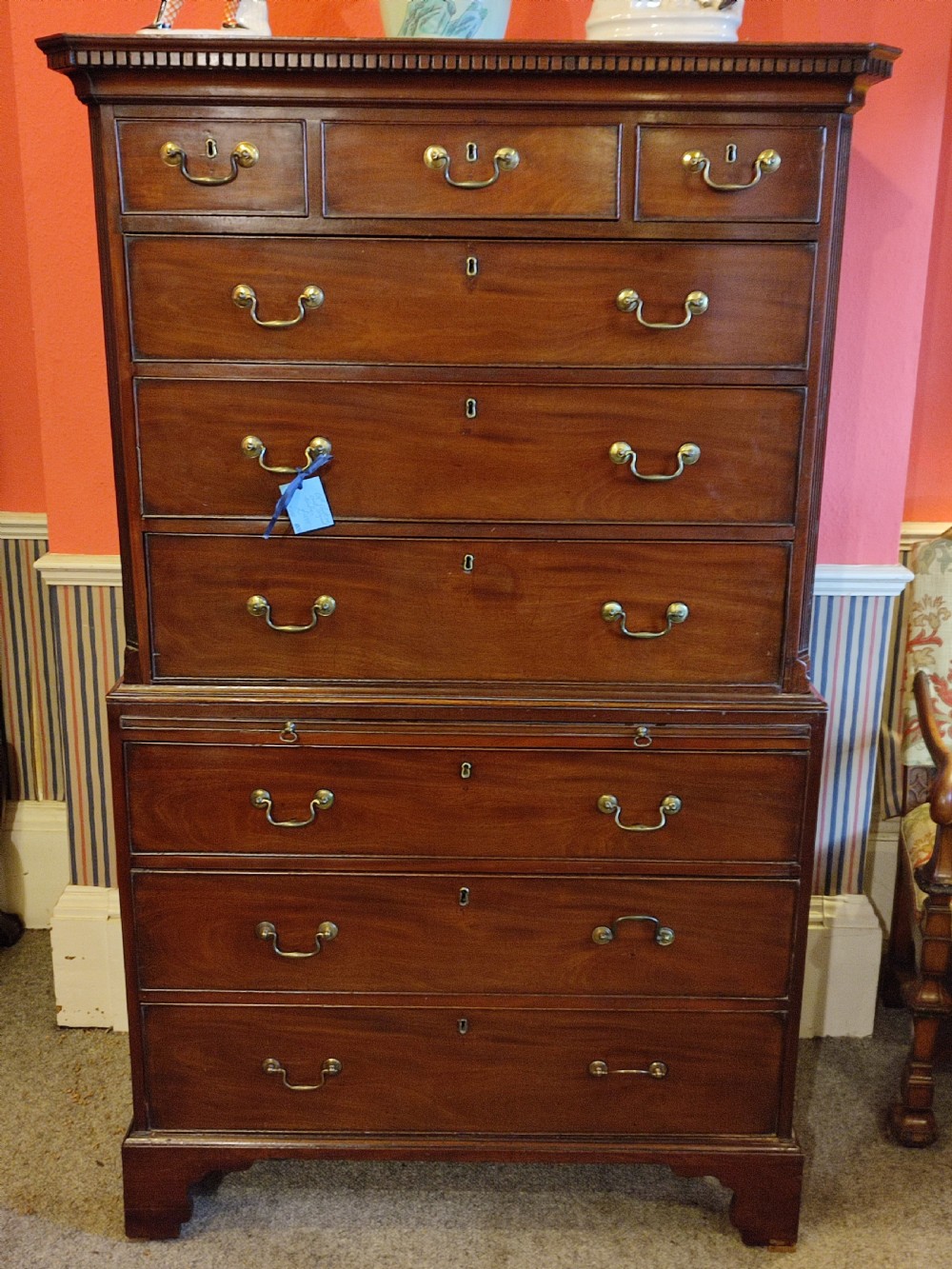 An 18th-century Georgian mahogany chest on chest featuring original brass swan-neck handles, dentil moulding along the cornice, and bracket feet.