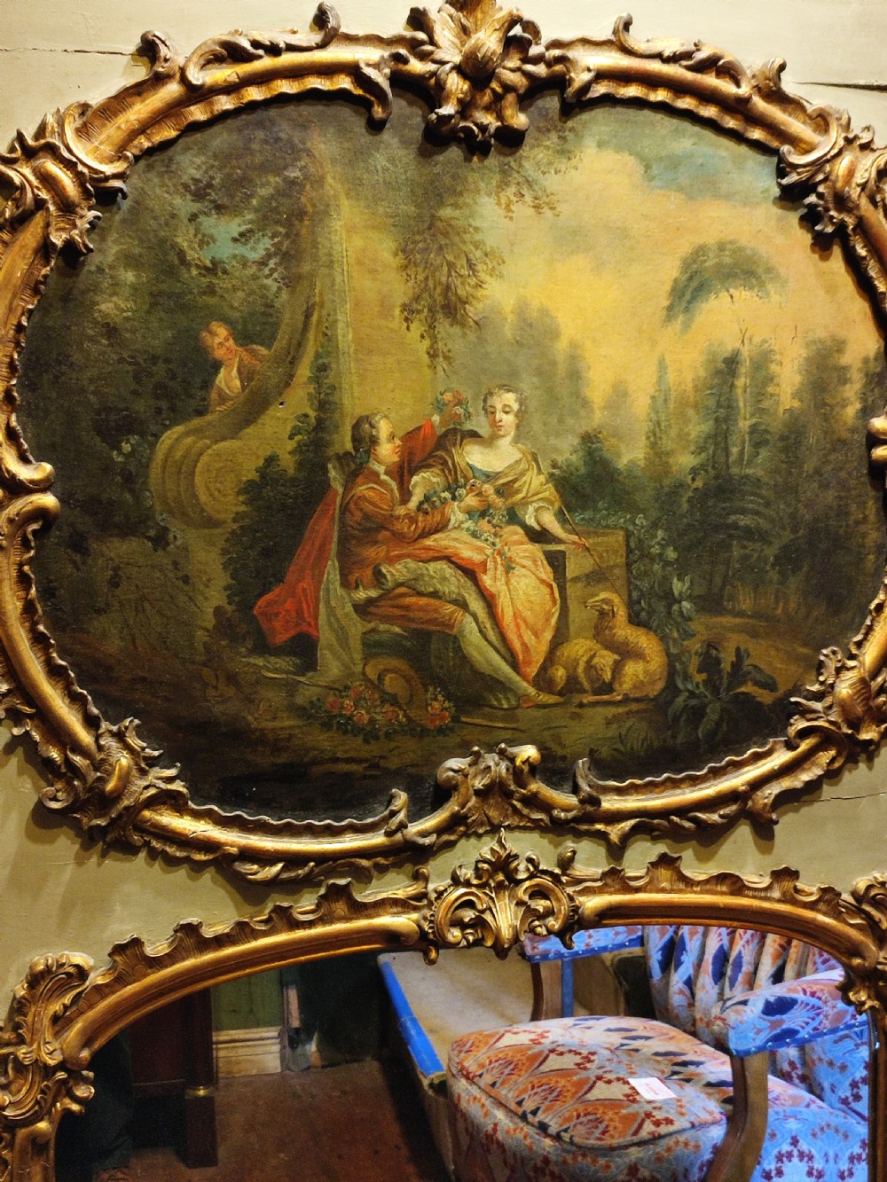 A large nineteenth-century French trumeau mirror featuring a painted canvas of a romantic pastoral scene above a mirror glass, set within carved giltwood frames on a grey painted panel. View II