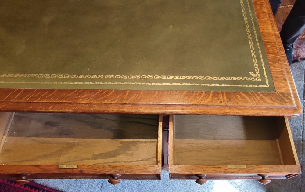 A nineteenth-century oak partners desk featuring a leather inset top, turned wooden knobs, and twin pedestal bases with drawers. View III