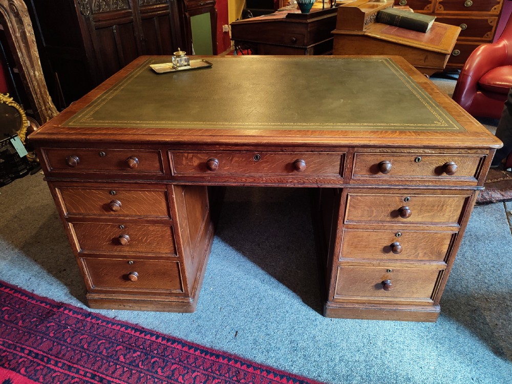 A nineteenth-century oak partners desk featuring a leather inset top, turned wooden knobs, and twin pedestal bases with drawers. View IV