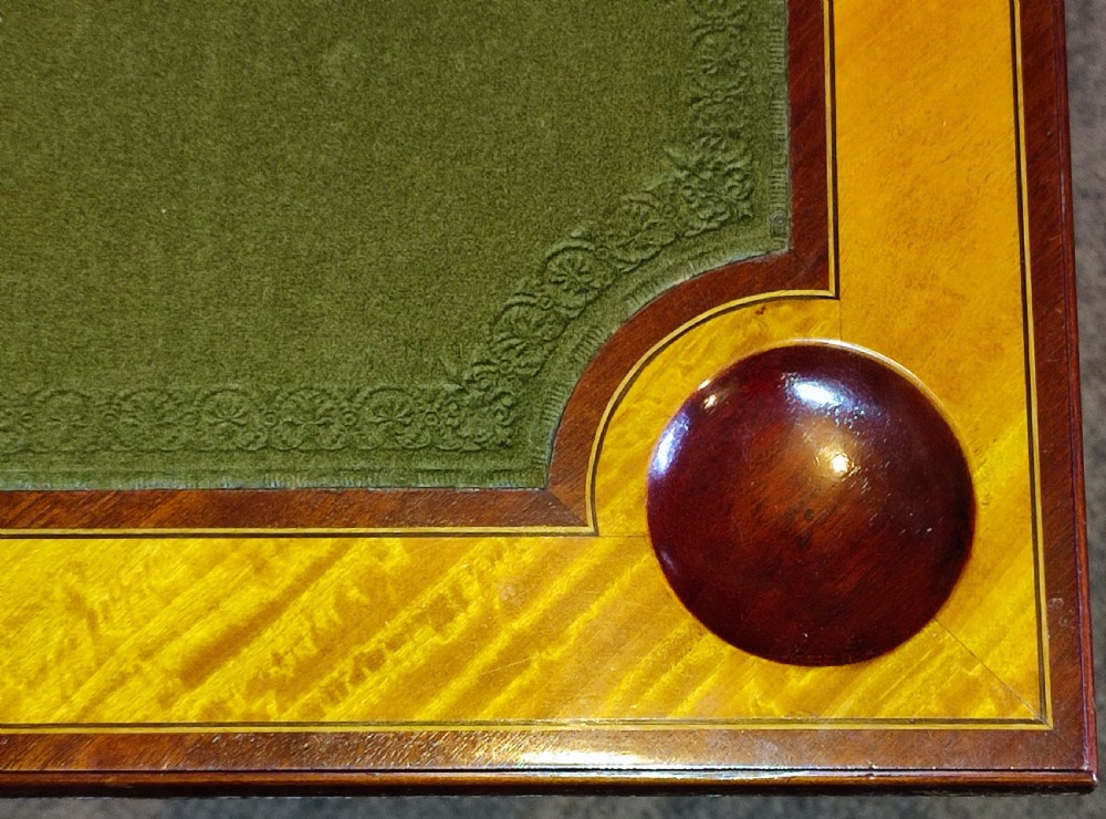 An Edwardian satinwood envelope card table featuring detailed marquetry inlays, four triangular top flaps, a single frieze drawer, and square tapered legs with a lower undertier. View V