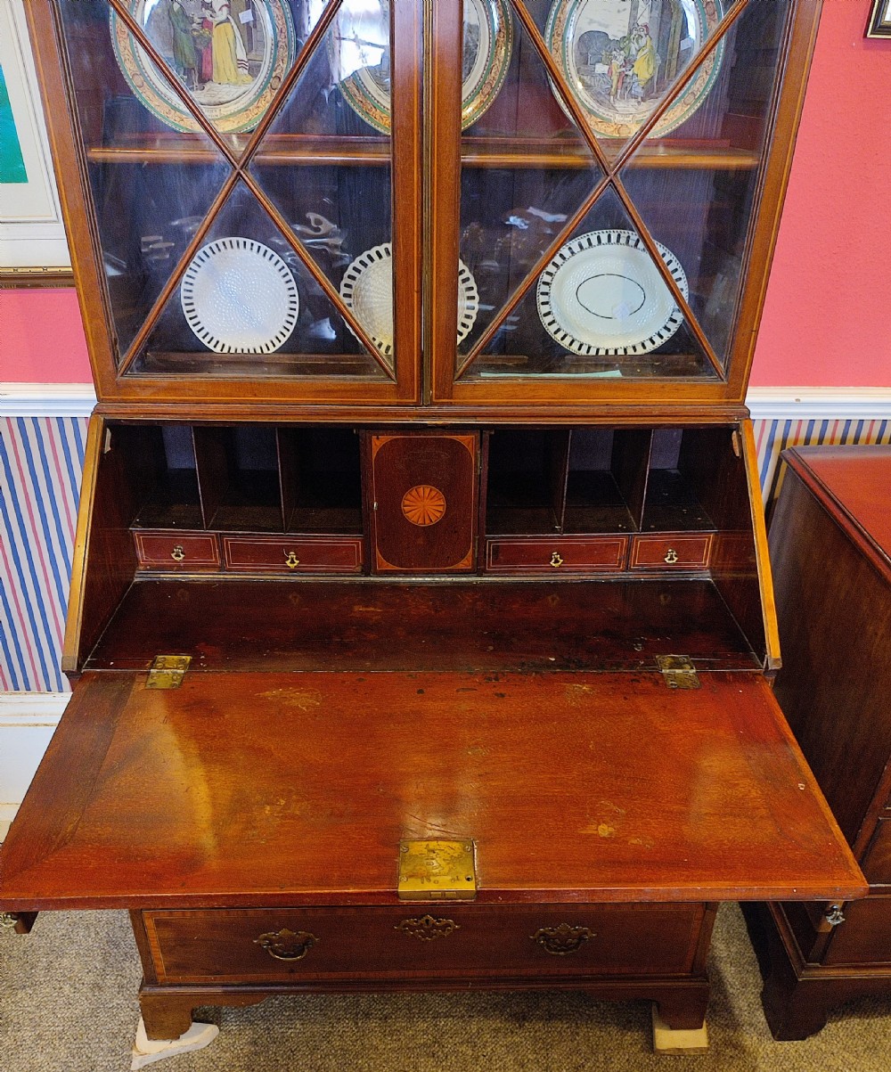 A tall George III mahogany bureau bookcase with a swan-neck pediment, diamond astragal-glazed upper doors, a slant-front writing slope, and lower drawers fitted with brass handles. View III