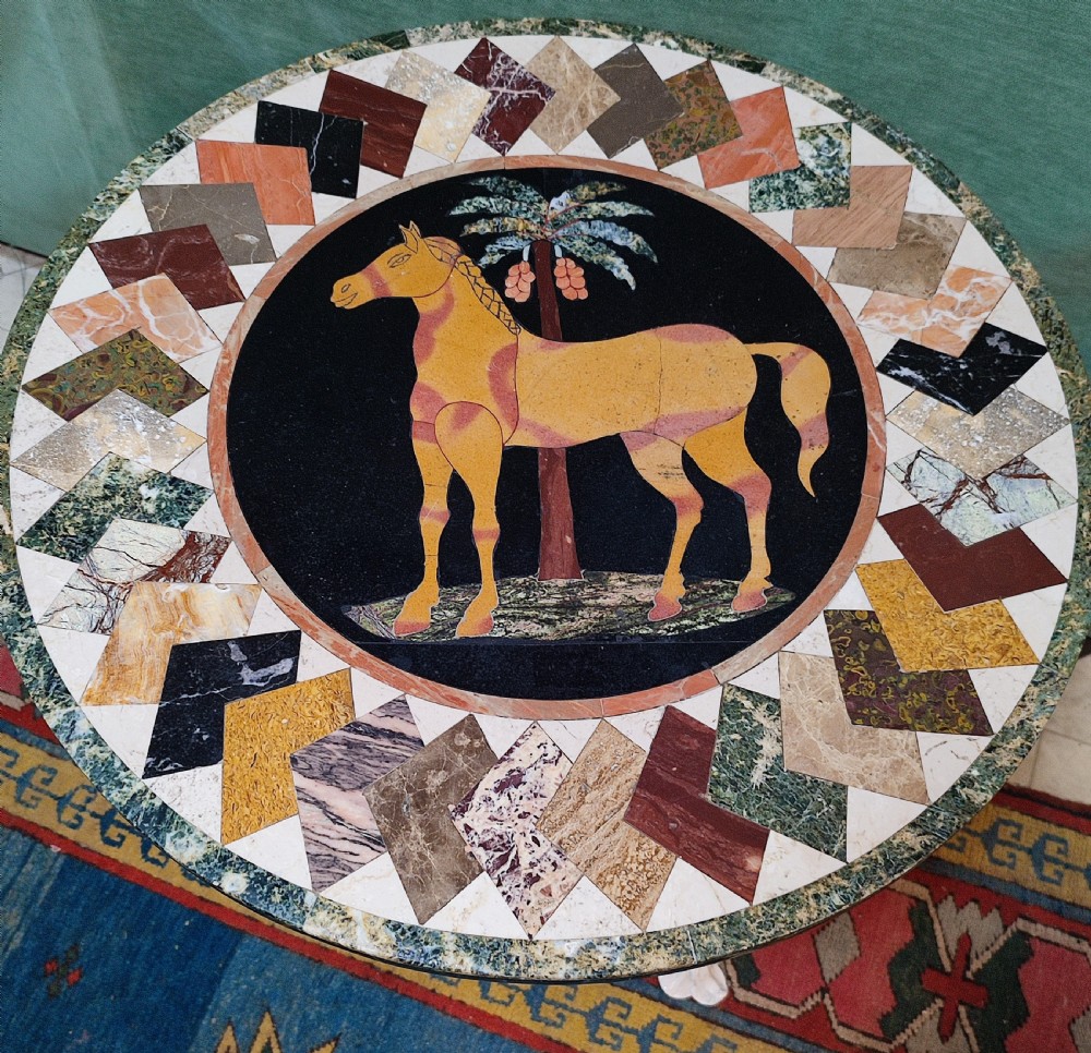 A circular specimen marble tabletop decorated with a central inlaid horse motif and geometric border, supported by a painted cream cast iron tripod base. View II