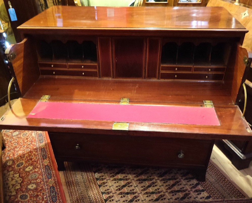 A Regency period mahogany secretaire chest with an open drop-front writing flap showing internal pigeonholes and miniature drawers.