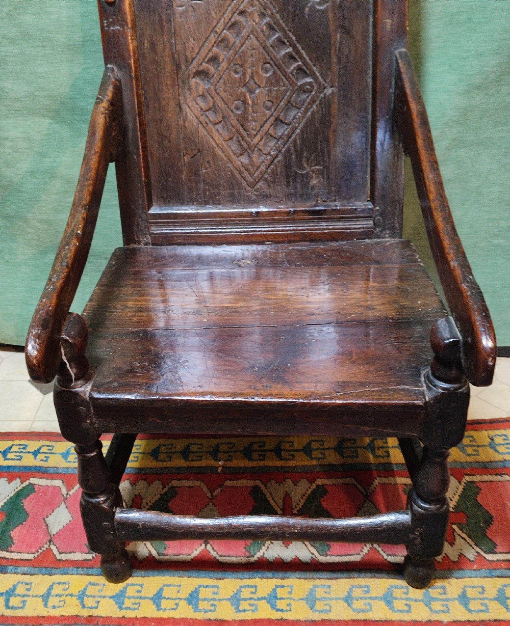 A 17th-century carved dark oak wainscot armchair featuring a carved lozenge back panel, carved initials on the crest rail, and turned front legs. View II