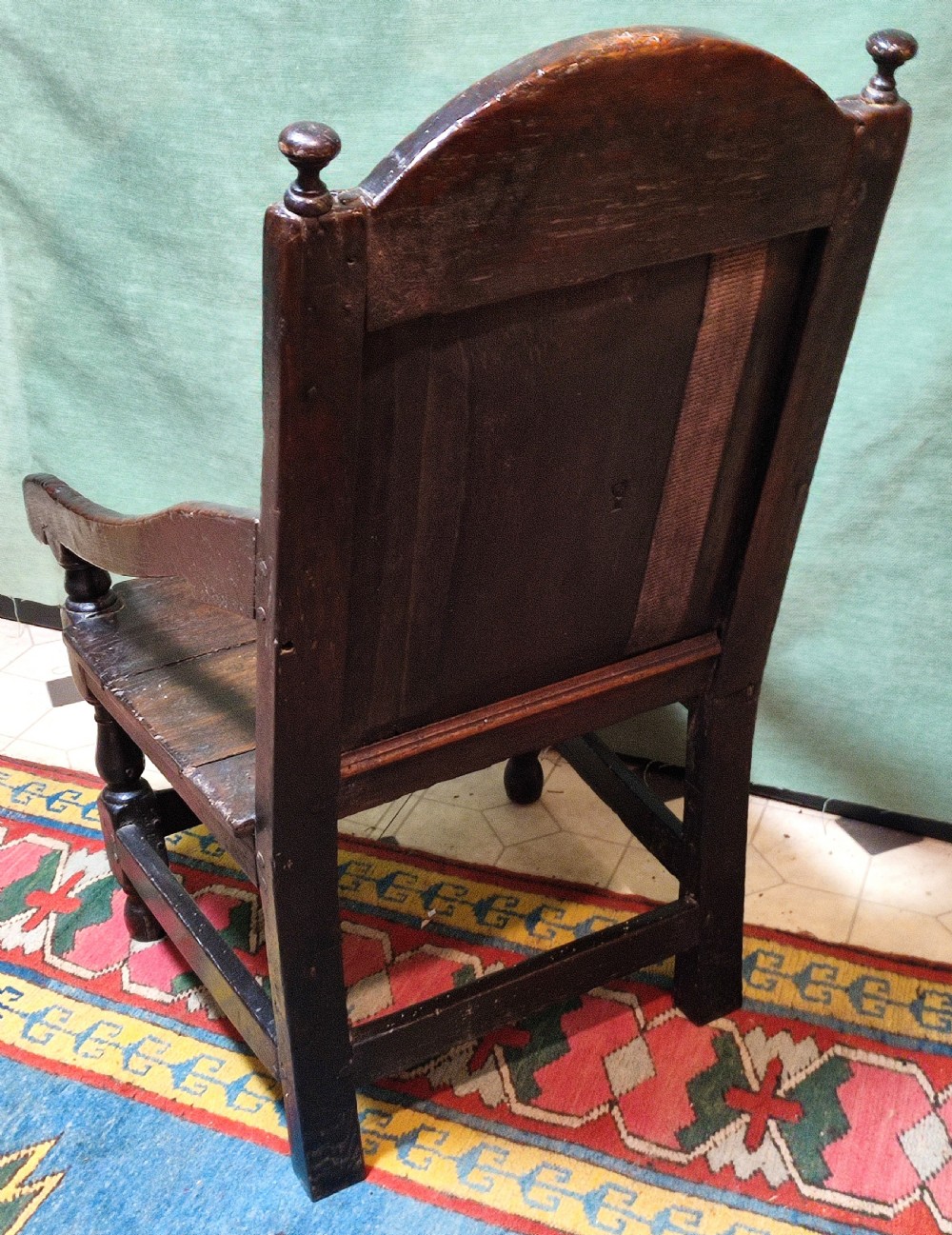 A 17th-century carved dark oak wainscot armchair featuring a carved lozenge back panel, carved initials on the crest rail, and turned front legs. View IV