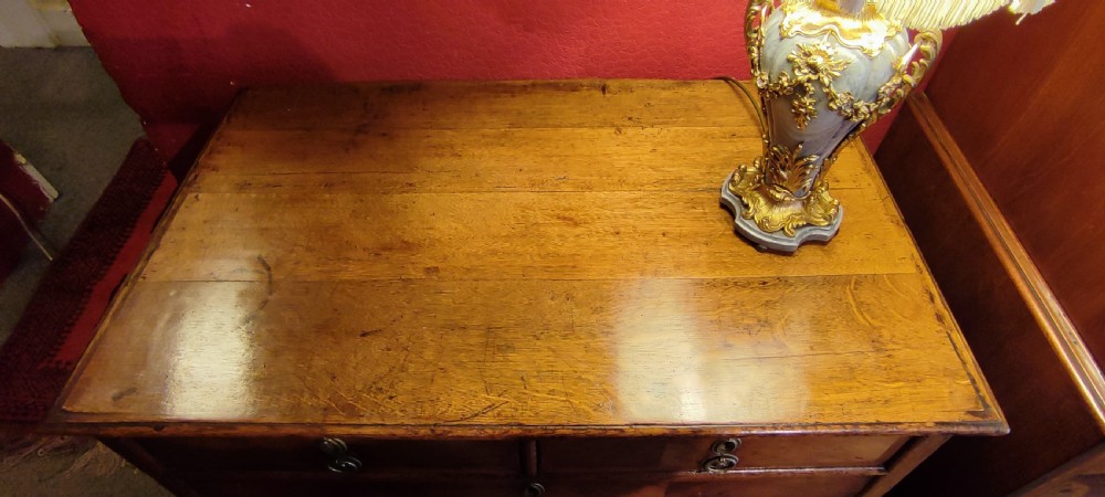 An antique William and Mary oak and walnut chest of drawers featuring two short over three long drawers with brass drop handles and a warm polished finish. View VI