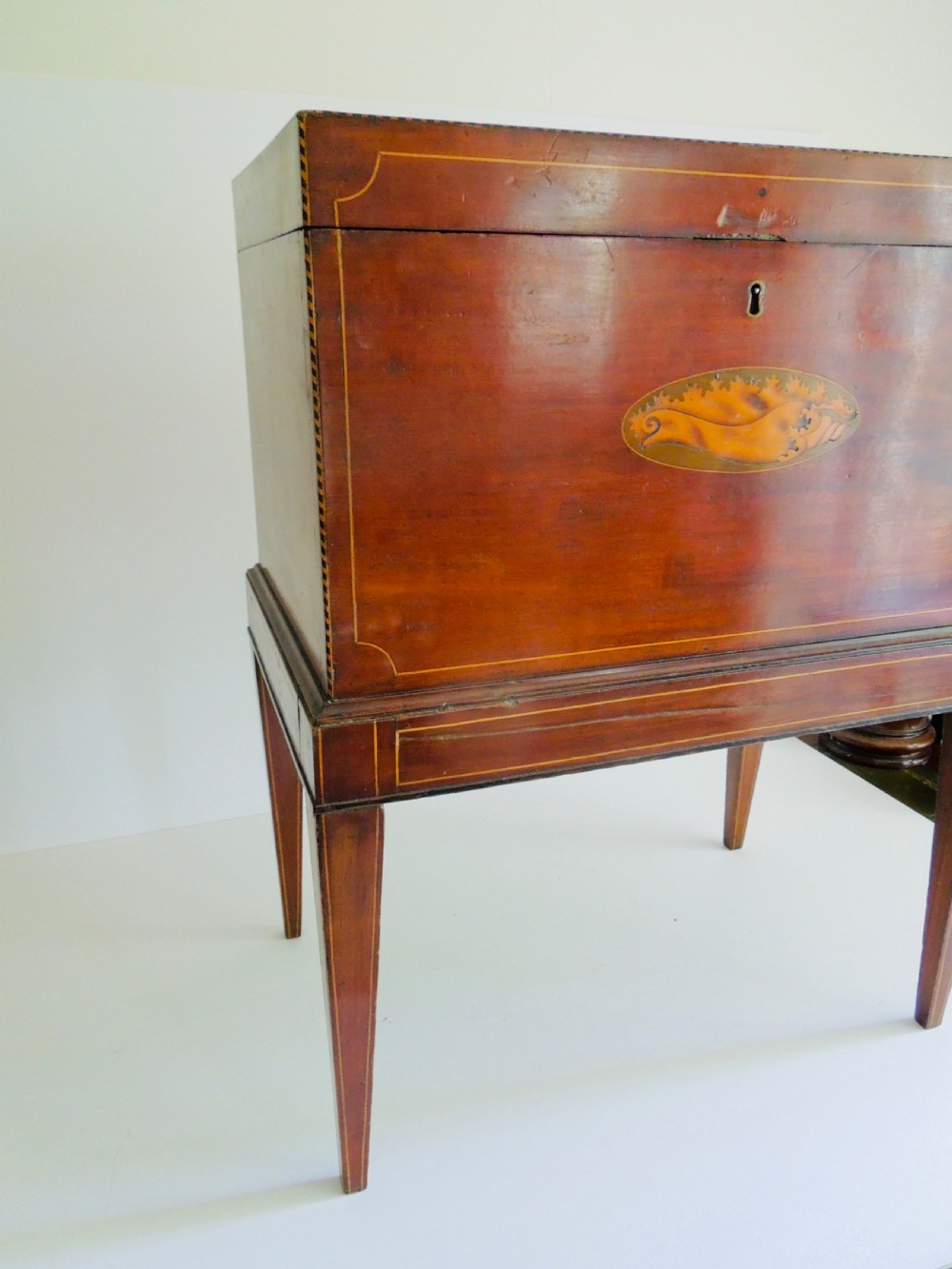 A Georgian mahogany wine cooler on square tapered legs featuring fine boxwood stringing and a central shell inlay medallion. View IV
